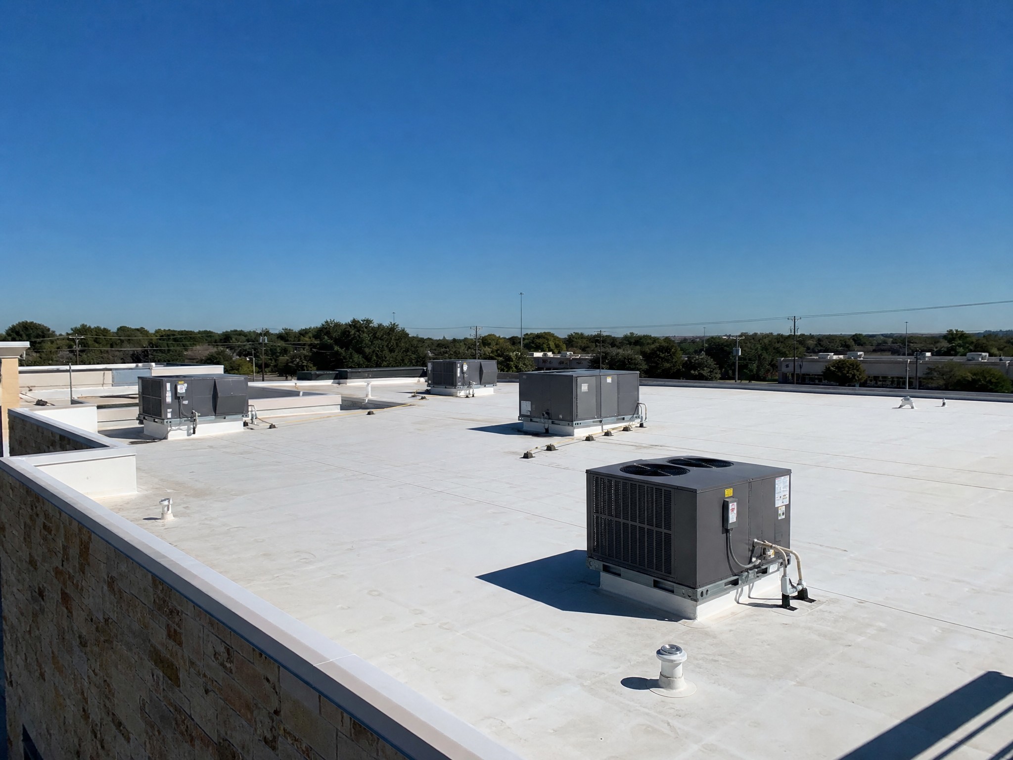 Flat TPO commercial roof on a Central Texas building under a clear sky